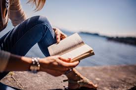 Woman reading a book beside a lake