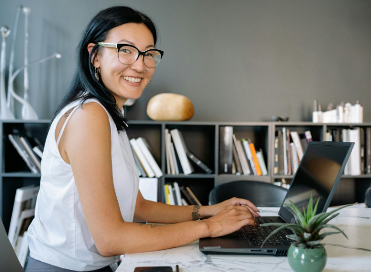 Smiling woman working typing on a laptop